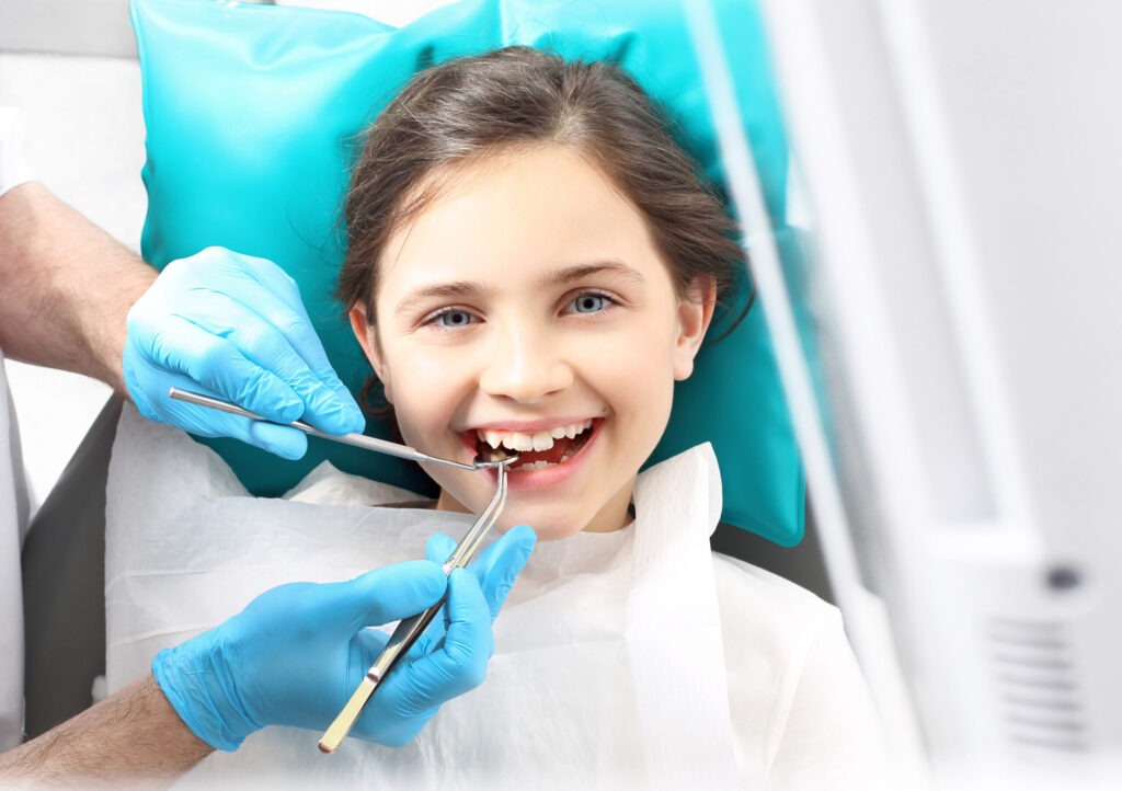 Little girl having teeth examined by dentist.