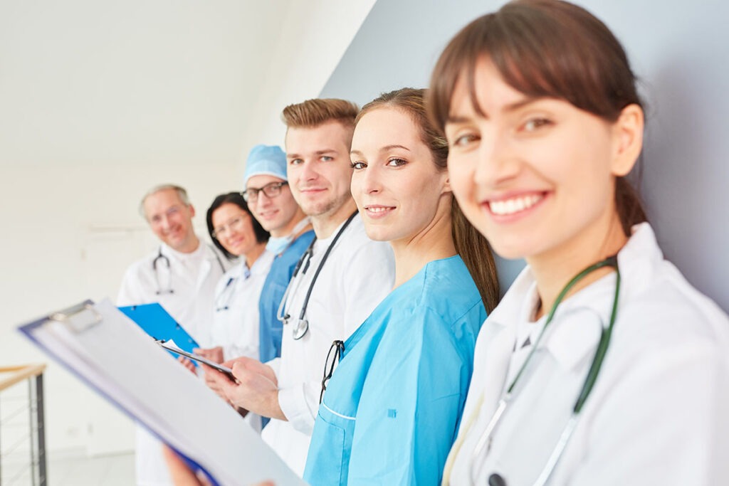 Group of health professionals smiling at camera along a wall.